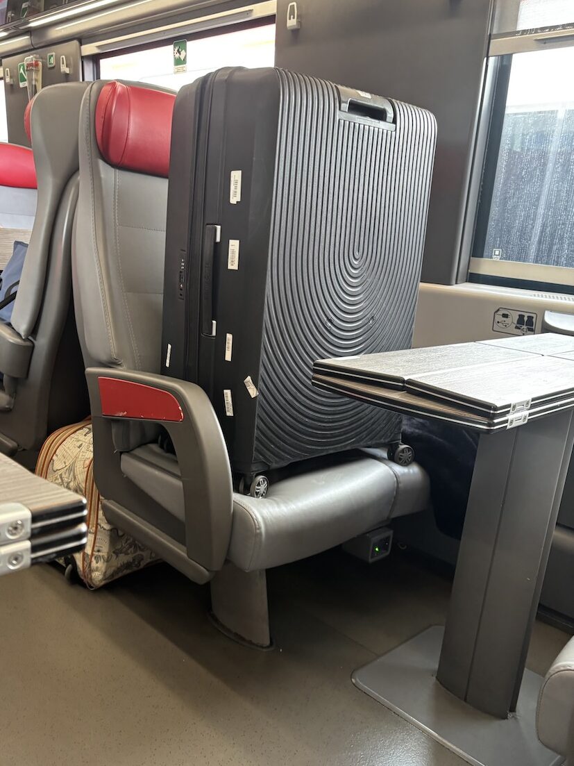 隣のボックス席の座席部分に大きなスーツケースが置かれている様子。