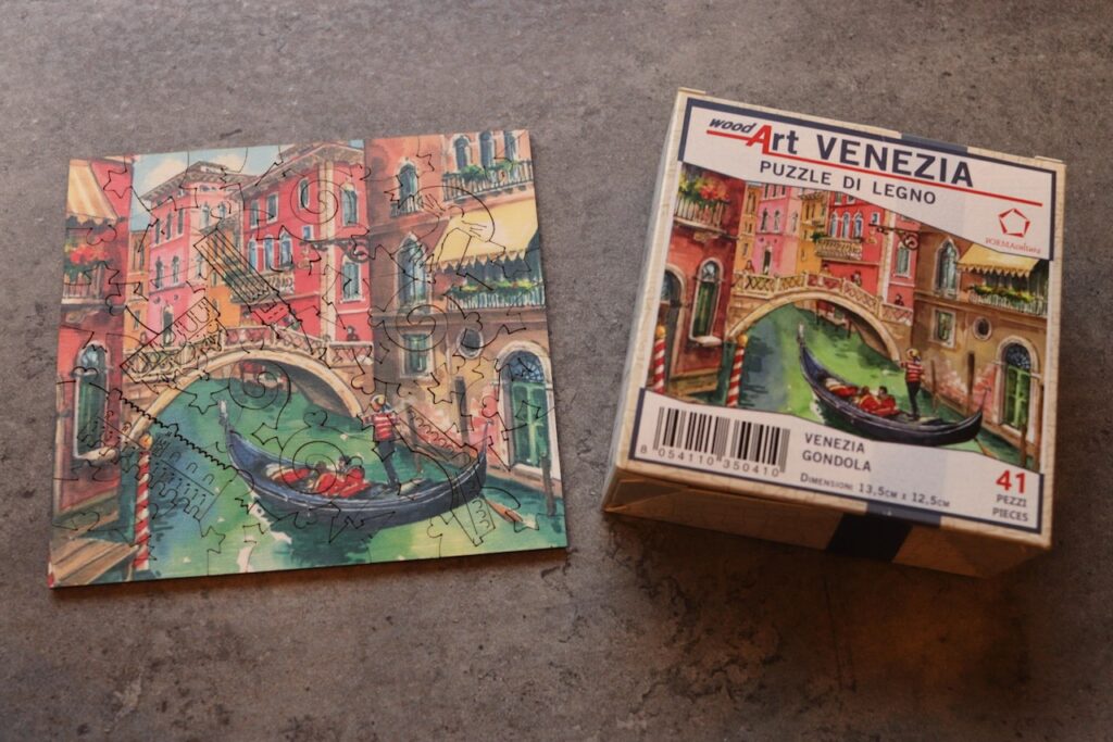 ブラーノ島で買えるヴェネチアお土産の木製パズル「PUZZLE DI LEGNO VENEZIA」。ゴンドラと運河の絵柄、41ピース。完成品と箱を並べて撮影。