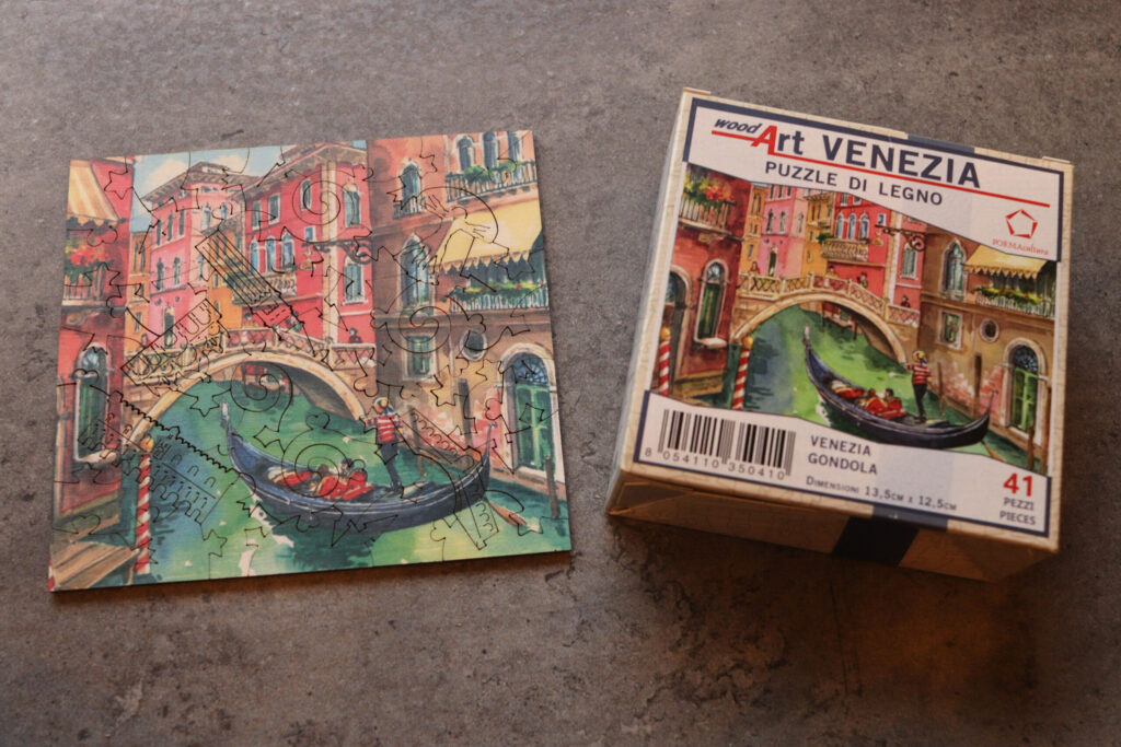 ブラーノ島で買えるヴェネチアお土産の木製パズル「PUZZLE DI LEGNO VENEZIA」。ゴンドラと運河の絵柄、41ピース。完成品と箱を並べて撮影。