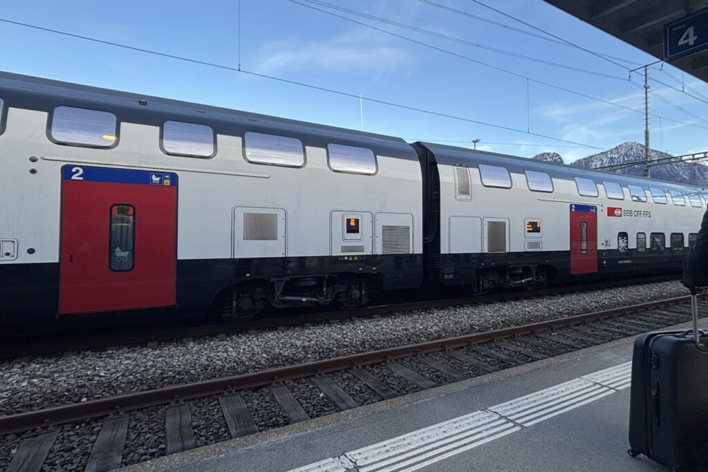 スイス鉄道SBBの2等車両とホーム。雪山を背景に停車中。